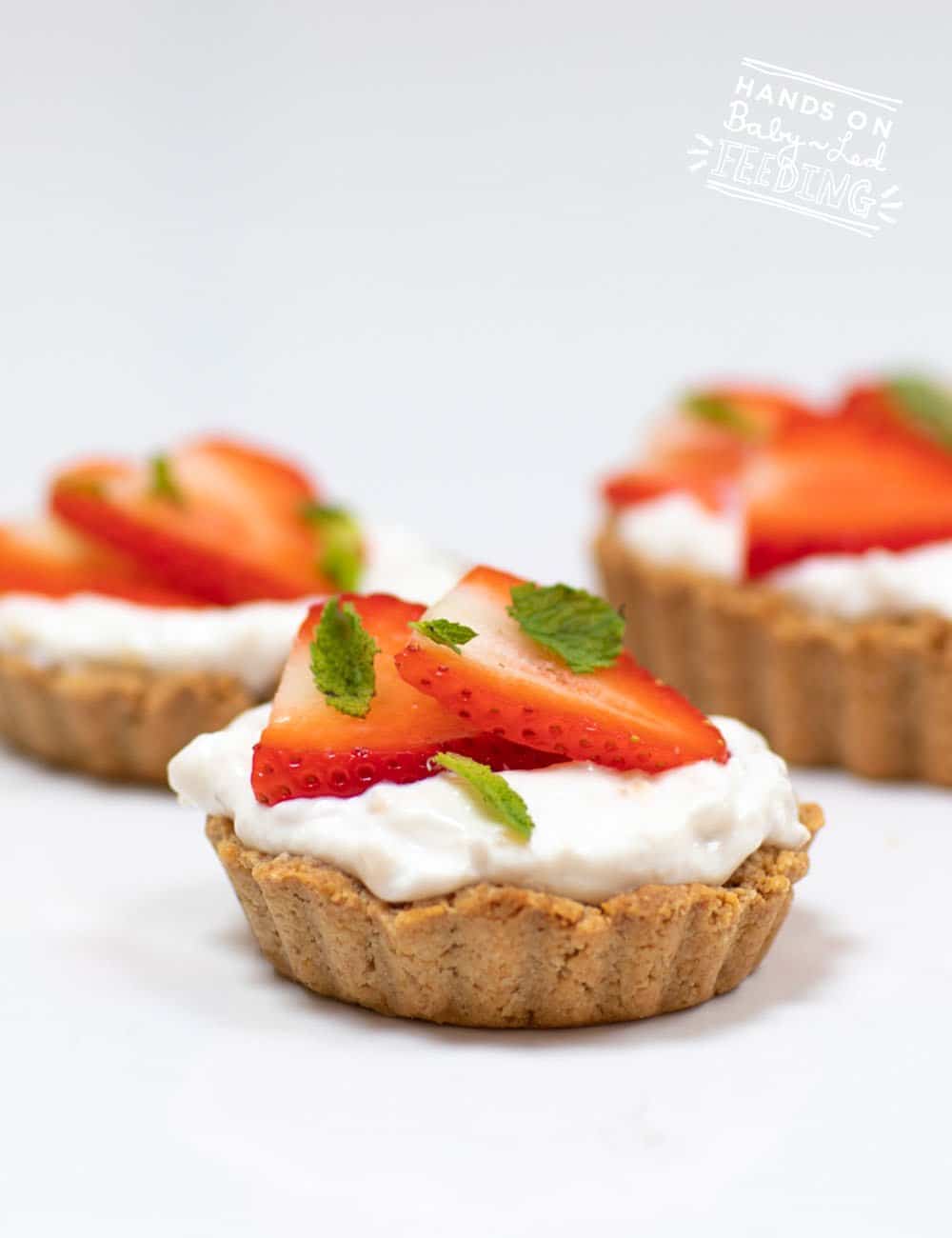 Strawberry Cream Tarts for baby led weaning are an easy healthy treat for the entire family. The simple oat crust crumbles gently making it safe for baby. A Greek yogurt cream filling lightly sweetened naturally with bananas. #babyledweaning #babyledfeeding #tarts #refinedsugarfree #healthytreats #strawberryrecipe